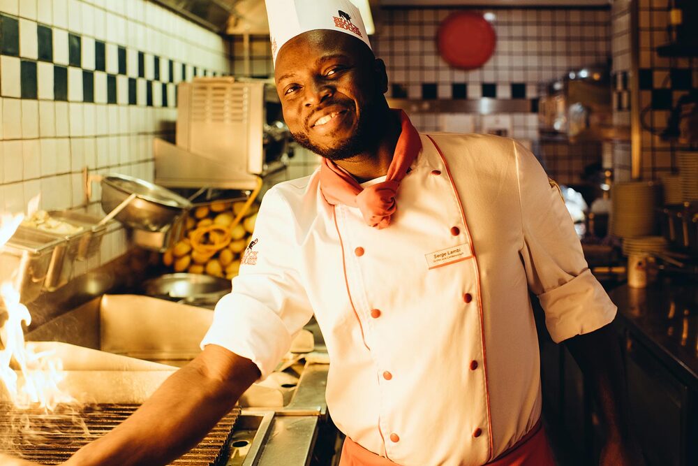 Griller im BLOCK HOUSE Restaurant Alstertal in Hamburg lächelt in die Kamera