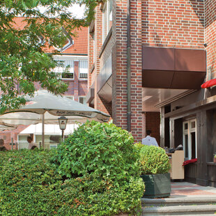 Hamburg Eidelstedt Außenfassade des BLOCK HOUSE Restaurants Eidelstedt in Hamburg. Links im Bild ist die Terrasse mit grüner Umrandung und Sonnenschirmen zu sehen.