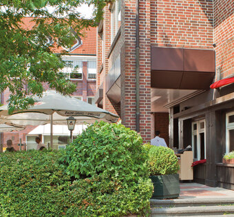 Hamburg Eidelstedt Außenfassade des BLOCK HOUSE Restaurants Eidelstedt in Hamburg. Links im Bild ist die Terrasse mit grüner Umrandung und Sonnenschirmen zu sehen.
